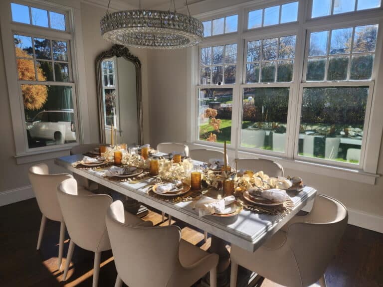 An elegant dining room set for a brunch with a chandelier, mirror, and gold accents