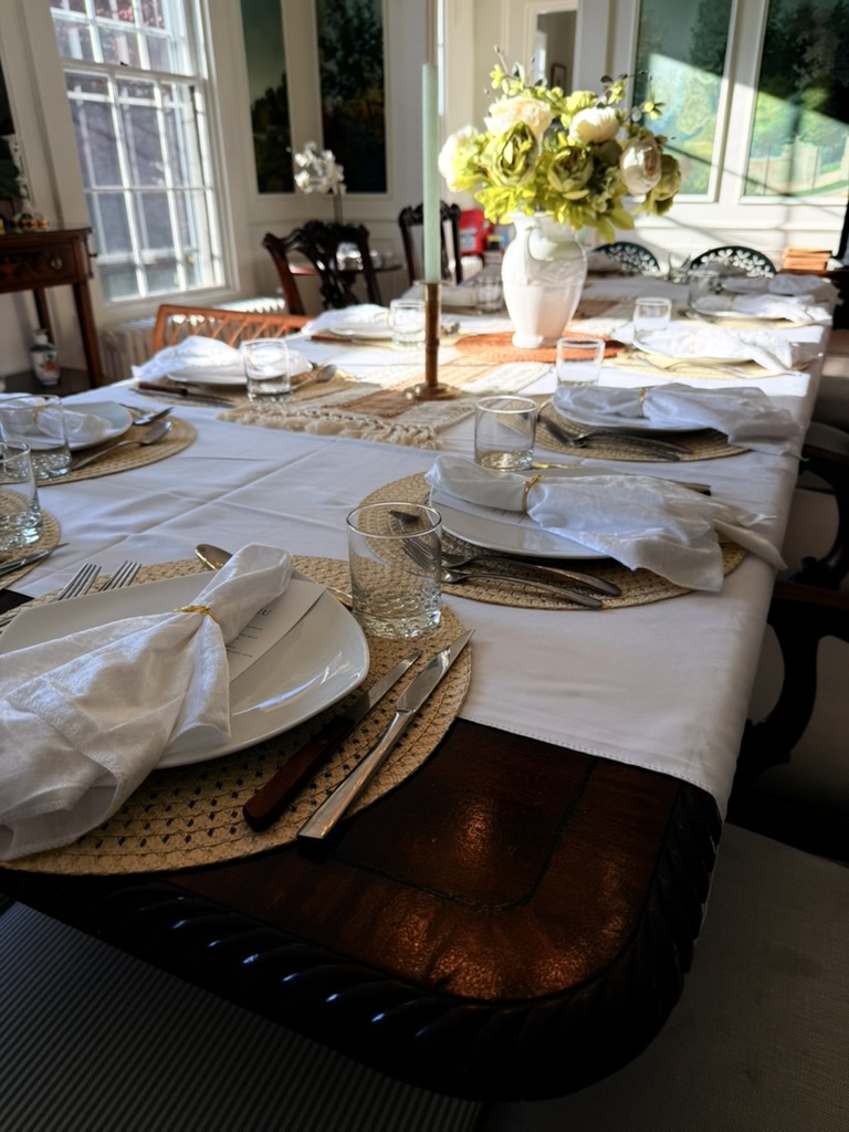 An intimate table set for an anniversary dinner with white tablecloth, candle, and floral centerpiece